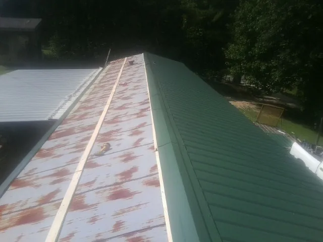 Old rusted panels beside newly installed green metal roofing in Pomona