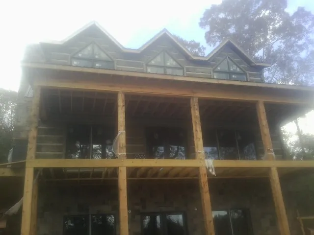 Dormers and porch framing on a large log home under construction — Roof Coating work by our crew in Pomona